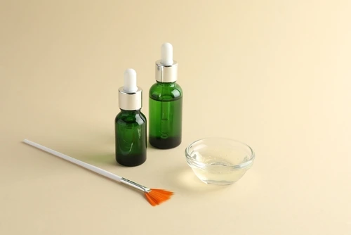 Bottles of chemical peel, bowl with liquid and brush
