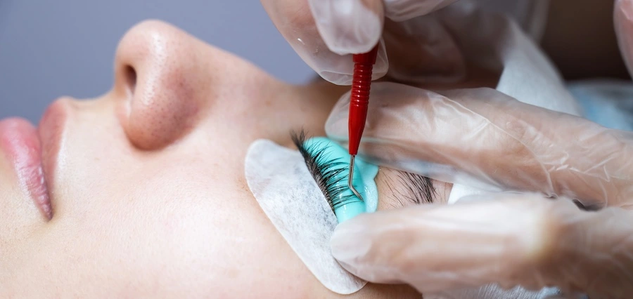 A person is undergoing a lash & brow tinting procedure.