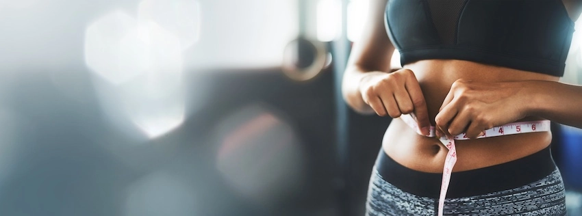 A woman is showing the progress she has made in weight loss management.